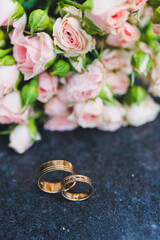 Precious gold rings for newlyweds on a background of flowers. Wedding rings for a couple.