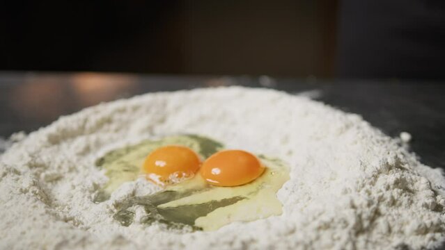 Hand Of Chef Cracking Eggs Into Flour For Dough Pasta Tagliatelle
