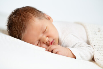 Sleeping Baby. Close up Newborn Face Portrait with long Hair. One month Boy sleep on Stomach under...