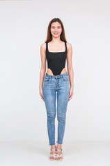 Young Asian woman in a black bodysuit and blue jeans standing on a white background