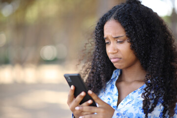 Disappointed black woman using cell phone