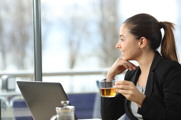 Happy businesswoman drinks tea and thinking in a bar