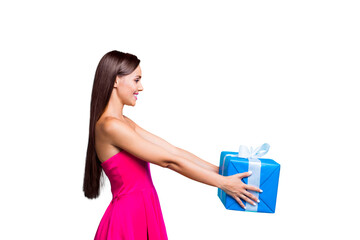 Side profile view of young straight-haired sweet tender brunette smiling girl with long hair, wearing pink dress, giving blue box with white ribbon. Isolated over bright vivid turquoise background