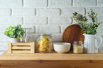 Kitchen table with food jars and plants over white brick wall  background.  Kitchen mock up for...
