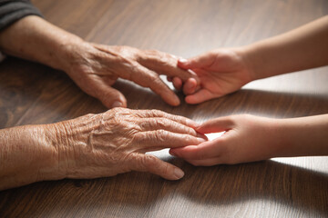 Elderly female and child hands together.