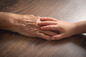 Elderly female and child hands together.