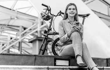 Confident businesswoman ride bicycle sit outside at downtown. Environmentalist commuting by cycling...
