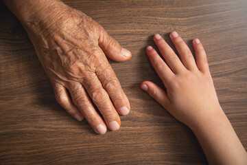 Elderly female and child hands together.