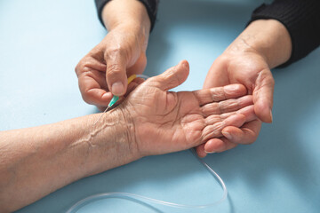 IV drip connected to a dropper a sick elderly woman.