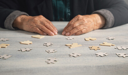 Old female hands with a jigsaw puzzle.