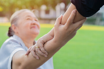 Hand of nurse helping senior Asian woman to exercise and holding hands at park