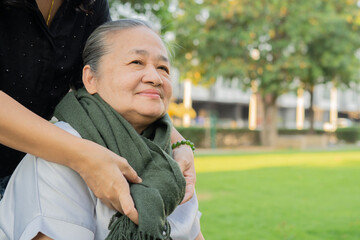 Happy active Asian senior woman with caregiver having fun outdoors. Friendship concept.