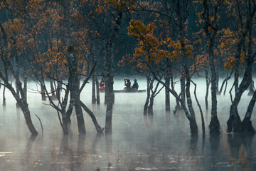 Foggy morning on the stream and the old man on the boat and the dog on the Tia stream, Da Lat. Extremely beautiful scene. Photo taken in Da Lat on January 4, 2004