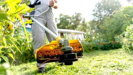 male gardener mowing the lawn in the garden