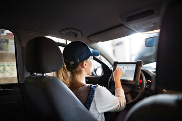 Female auto mechanic using diagnostic tool, scanner, running diagnostic on car. Beautiful woman...