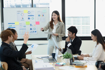 Asian group of people working with documents have financial or marketing charts on a board room table at a business presentation or seminar.