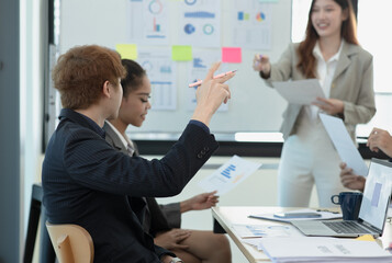 Group of asian business people working and brainstorming in workshop and analyzing marketing reports startup project infographics in the office, Sales and business plans, presentation ideas concept.