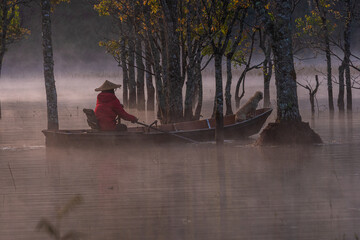 Foggy morning on the stream and the old man on the boat and the dog on the Tia stream, Da Lat. Extremely beautiful scene. Photo taken in Da Lat on January 4, 2004