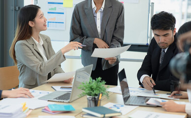 Group of asian business people working and brainstorming in workshop and analyzing marketing reports startup project infographics in the office, Sales and business plans, presentation ideas concept.