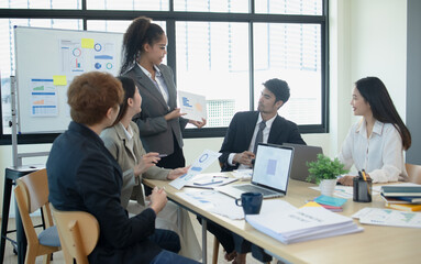 Group of asian business people working and brainstorming in workshop and analyzing marketing reports startup project infographics in the office, Sales and business plans, presentation ideas concept.