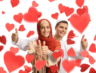 Young man and woman in ethnic clothes showing thumbs up under red hearts