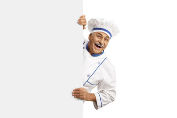 Mature male chef in a uniform peeking behind a blank panel