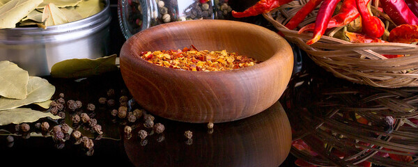 Wooden bowl of chili flakes, bay leaf, black pepper - obrazy, fototapety, plakaty