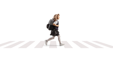 Full length profile shot of a schoolgirl in a uniform carrying a backpack and running at a...