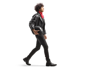 Full length profile shot of a of a young man in leather jacket walking and holding a motorbike...