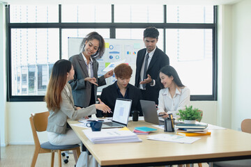 Asian group of people working with documents have financial or marketing charts on a board room table at a business presentation or seminar.
