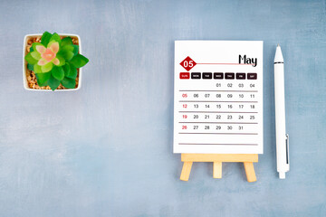 2024 May calendar page and pen with plant pot on wooden background.