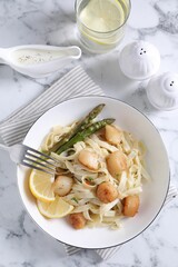 Delicious scallop pasta served on white marble table, flat lay