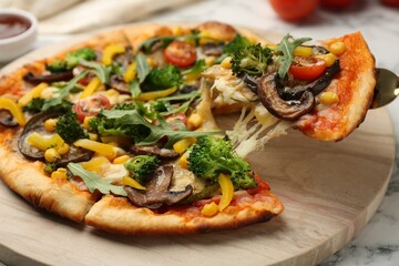 Taking piece of delicious vegetarian pizza at table, closeup