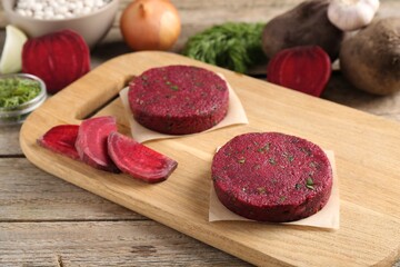 Vegetarian product. Uncooked beetroot cutlets and ingredients on wooden table
