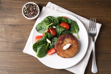 Tasty vegetarian cutlet served with vegetables on wooden table, flat lay