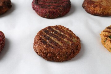 Different tasty vegetarian cutlets on parchment paper, closeup