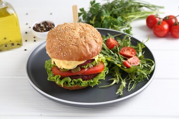 Delicious vegetarian burger served with salad on white wooden table