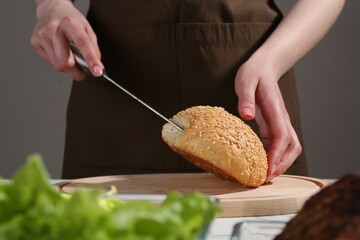 Woman making delicious vegetarian burger at table, closeup