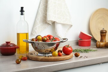 Metal colander with tomatoes on countertop in kitchen