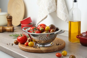 Metal colander with tomatoes on countertop in kitchen