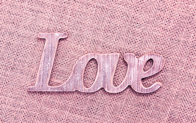 Wooden letters forming word LOVE written on sackcloth background