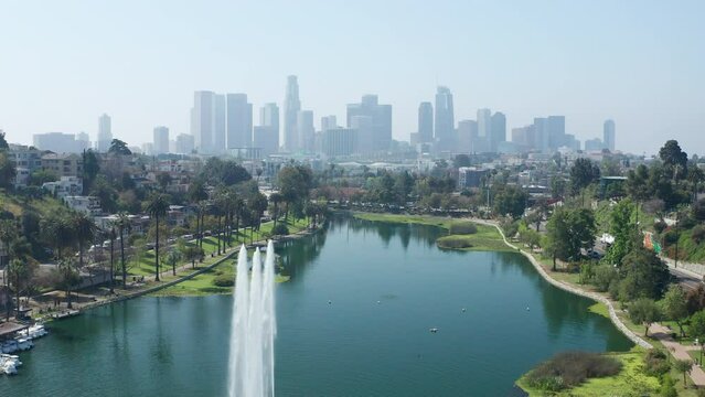 Beautiful shot of Echo Park lake fountains and downtown skycrapers towers palm