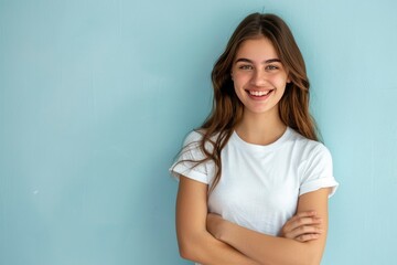 beautiful woman smiling with arms crossed wearing white tshirt on light blue background