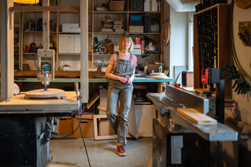 Serene woman carpenter take break after production wooden DIY furniture in joinery workshop...