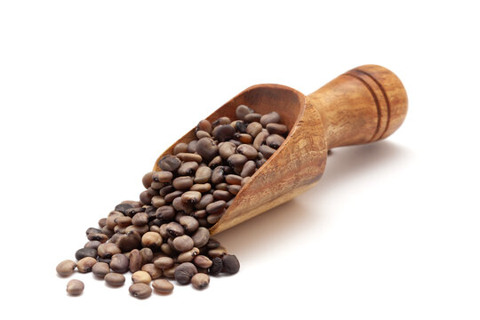 Front view of a wooden scoop filled with dry Organic cluster bean  (Cyamopsis tetragonoloba) seeds. Isolated on a white background.