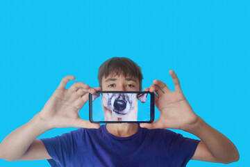Portrait of a young guy with a smartphone in his hands, image of a dog on the smartphone