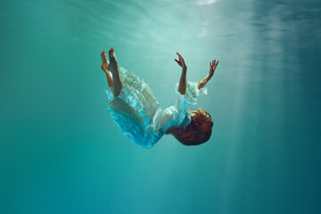 Falling into unknown. Surreal underwater creative scene featuring elegant young woman levitating gracefully underwater. Concept of surrealism, beauty, mystery and fantasy, freedom
