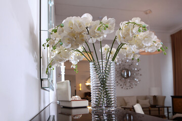 A bouquet of white orchids in the interior. Artificial flowers in a vase. A vase with beautiful...
