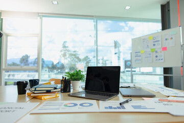 Laptop at office desk, graphs and charts, analysis report chart in office workspace.