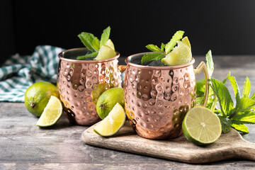 Moscow mule cocktail served with ice and lime slice on wooden table.